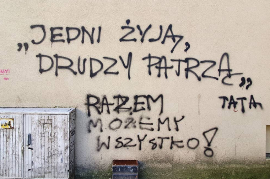 Poznań Napis na murze Jedni żyją drudzy patrzą Razem możemy wszystko